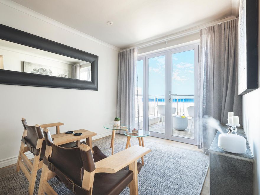Helle, moderne Suite mit Balkon und Meerblick, Ledersesseln und Holzmöbeln in der Beach Villa Wilderness