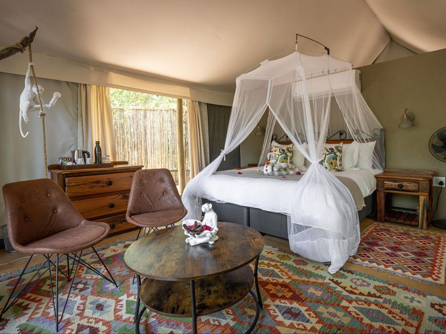 Interni di lusso delle tende safari con letti a baldacchino singoli, tappeti colorati e moderna area lounge all'Umkumbe Bush Lodge.