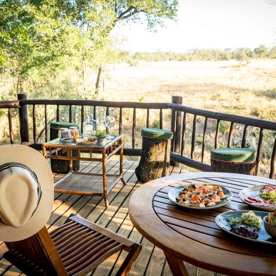 Cena safari sulla terrazza privata con vista sulla savana africana all'Umkumbe Bush Lodge, con piatti serviti al tavolo e cappello da safari