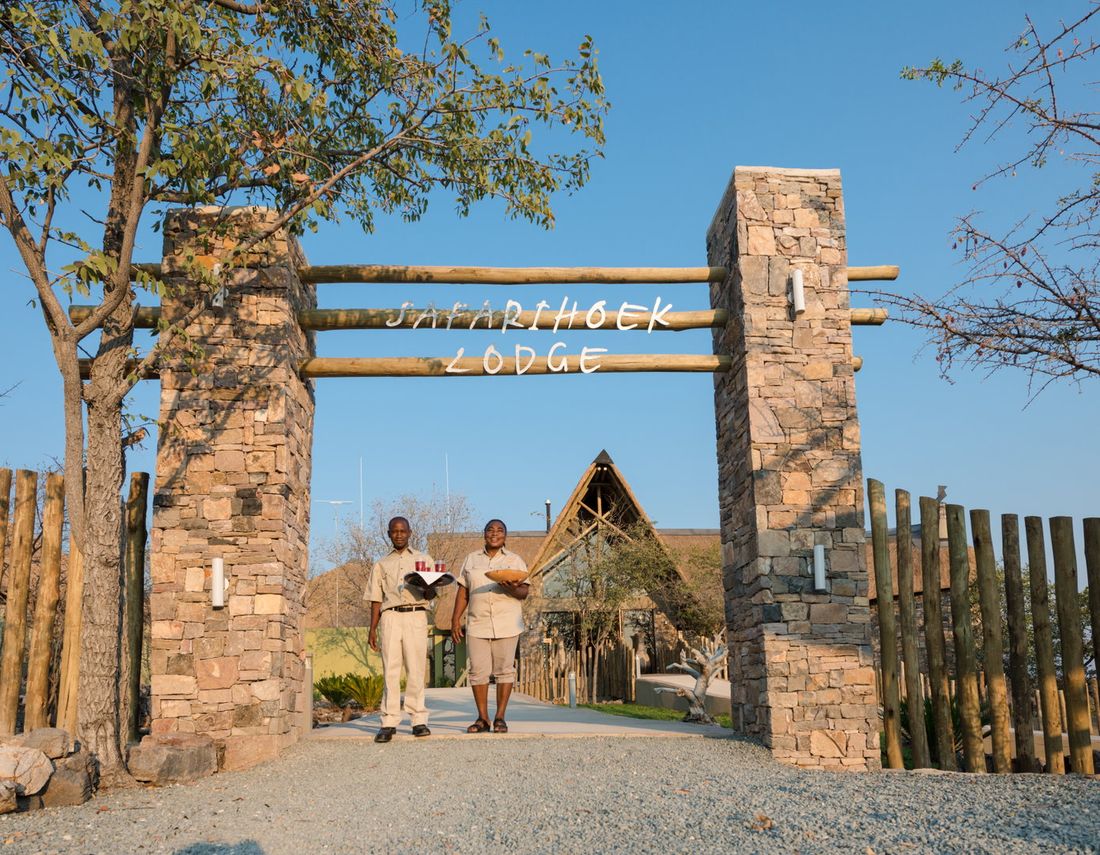Deux membres du personnel de Safarihoek attendant d'accueillir les visiteurs à l'entrée en pierre du Safarihoek Lodge