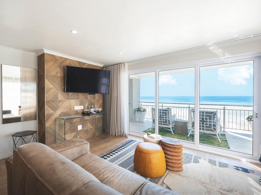 Luxuriöse Suite direkt am Strand mit Balkon und Meerblick, modernen Holzwänden, Flachbildfernseher und bequemen Sitzgelegenheiten in der Beach Villa Wilderness.