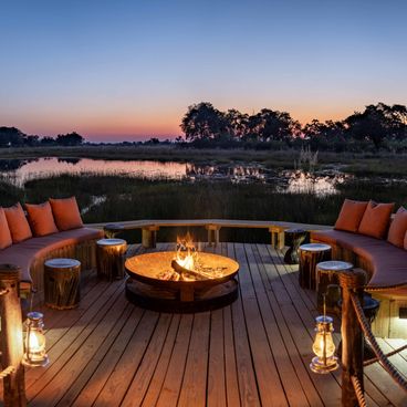 Sunset fire pit deck with curved seating overlooking Okavango Delta wetlands at North Island luxury safari lodge